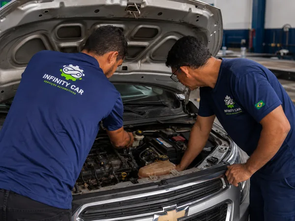 Dois mecânicos da Infinity Car trabalhando no motor de um carro